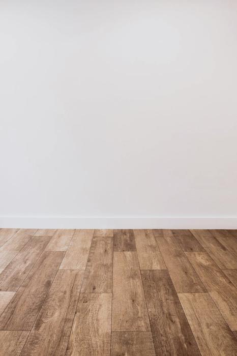 Clean white wall with wooden flooring offering versatile copy space.