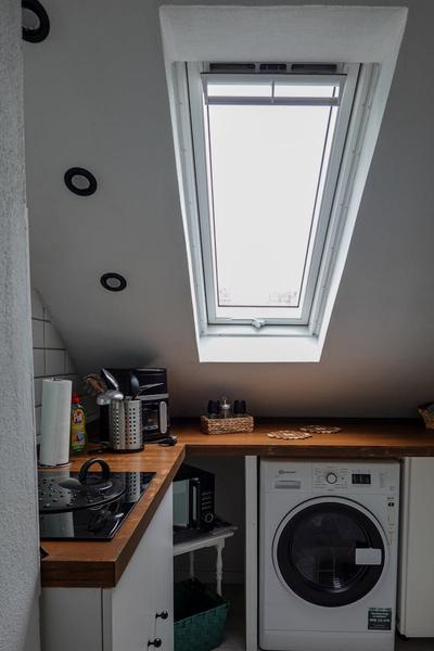 Cozy modern kitchen featuring a skylight window, washing machine, and countertop appliances.