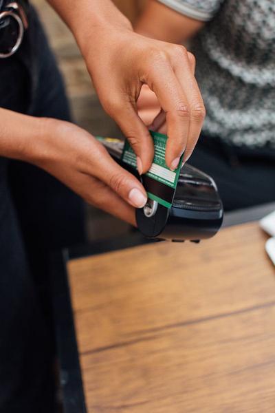 A person's hands doing a cashless transaction with a card reader.