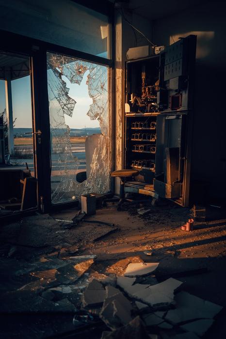 A moody scene of a broken vending machine and shattered glass in an abandoned room.