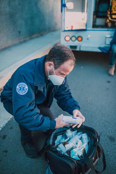 A paramedic arranges supplies outside an ambulance, focusing on emergency preparedness.